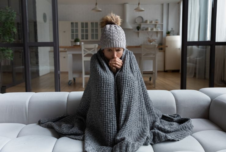 women with blanket over her shivering in the cold