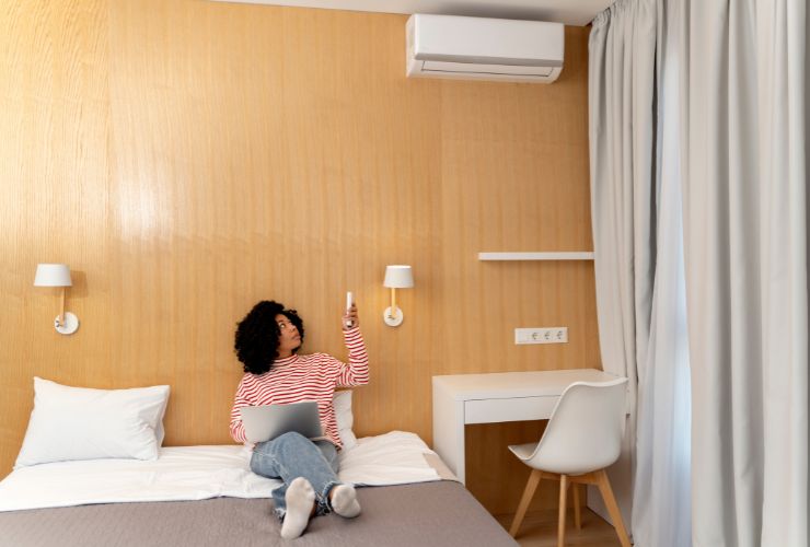 woman changing air conditioner temperature