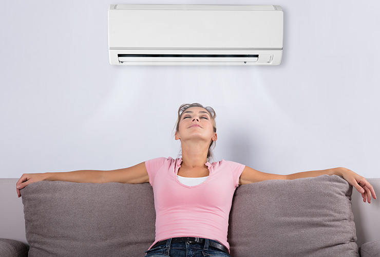woman sitting on couch enjoying air conditioner 