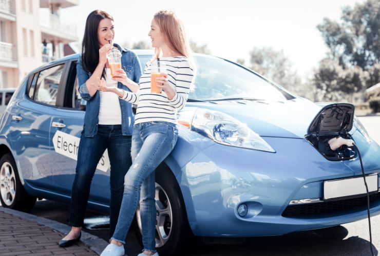 two women leaning on electric vehicle 