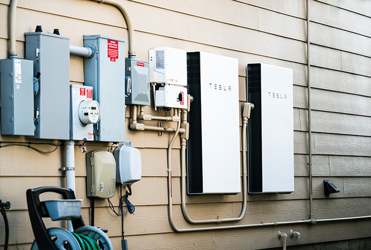 two Tesla solar batteries attached exterior to a a house.
