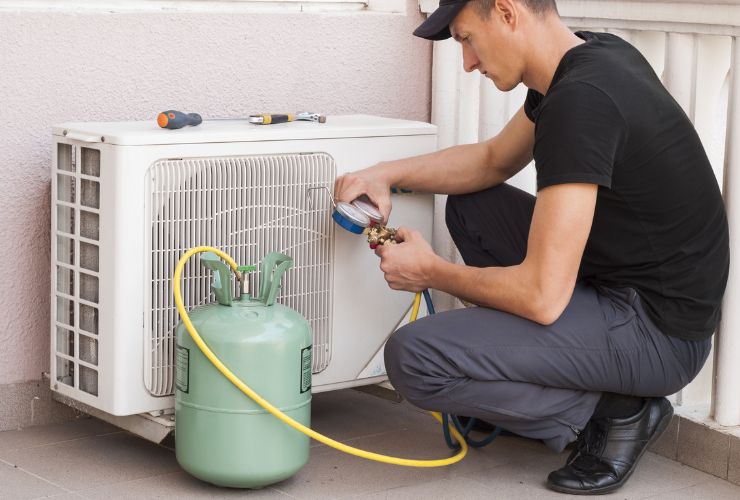 installer re-gassing an outdoor air conditioner unit