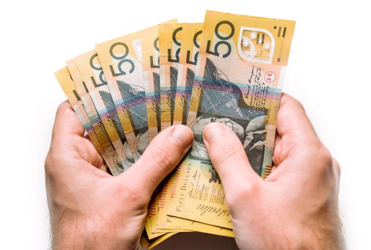 hand holding Australian money from solar hot water rebate