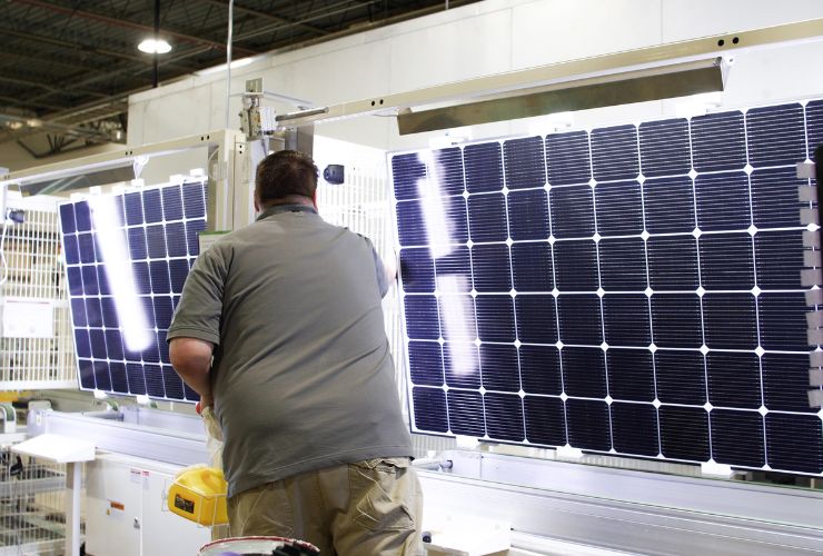 man inspecting a full-celled solar panel