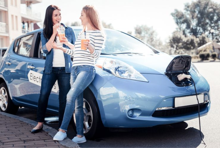 two women talking with an ev in the background