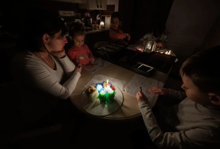 Family gathered around candles during blackout because they don't have solar and battery